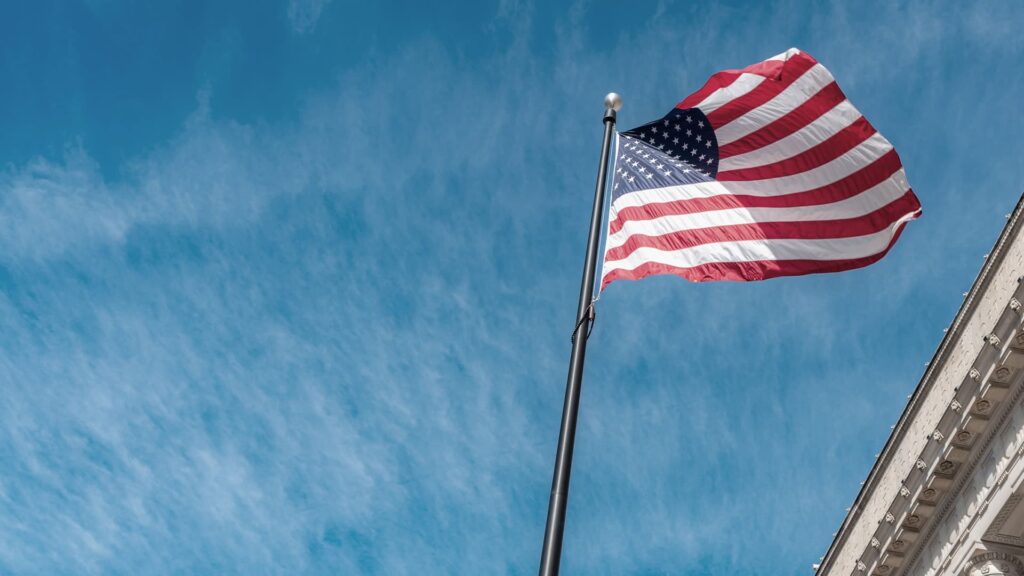 An American flag on a pole that is waiving in the wind