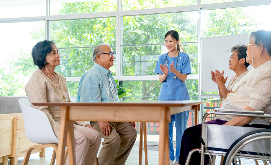 Northwind Group closes $342.5M Healthcare Debt Fund A stock image with a nurse standing behind a table, clapping, surrounded by seated patients in a nursing home-like facility. PHOTO: DEPOSIT PHOTOS