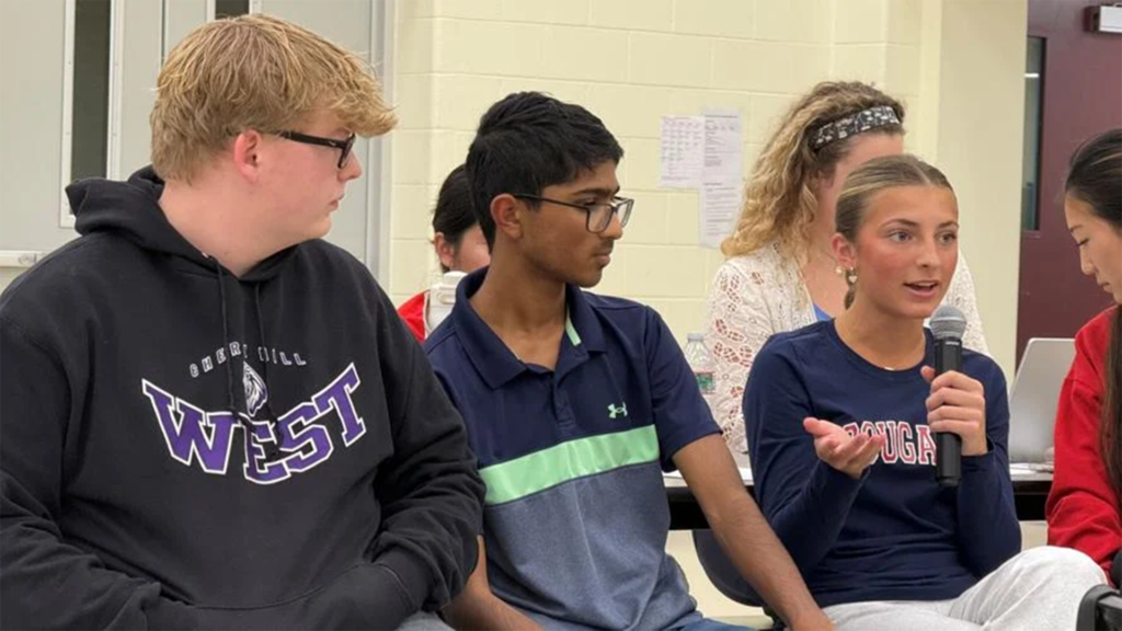 70and73: Cherry Hill schools ask for help with AI explosion Students seated together during a discussion, including a student speaking into a microphone while others listen.