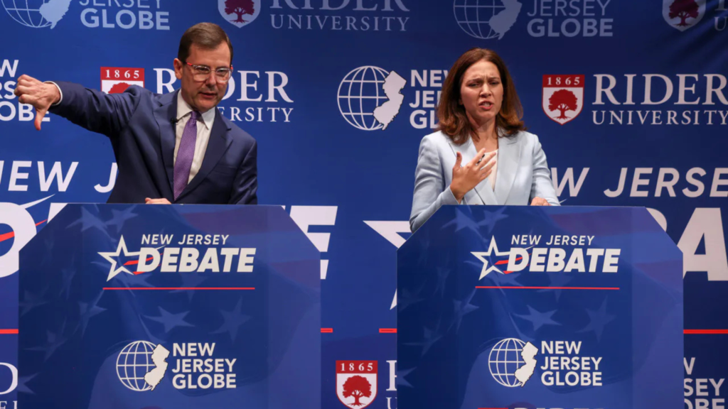 NJ’s hottest congressional race not short on cash Two candidates at blue debate podiums; a man gives a thumbs-down while a woman speaks with her hand on her chest.